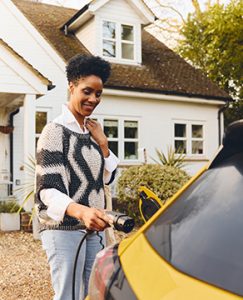 Woman,Charging,Electric,Car,On,Driveway,Outside,House - Auto Repair in York, PA Meineke Car Care | EV Battery Range | East Petersburg